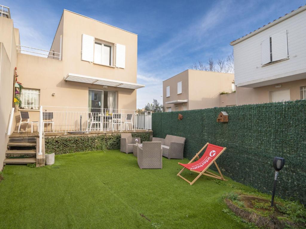 une cour avec une pelouse, une chaise et une clôture dans l'établissement Holiday Home Les Brigantines by Interhome, au Grau-du-Roi