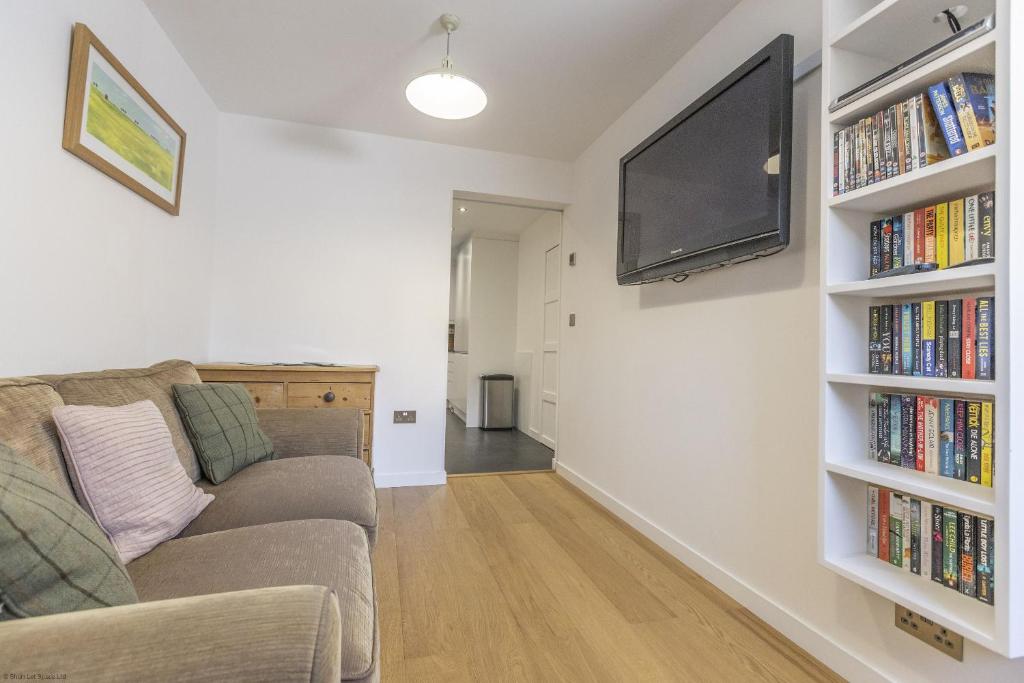 a living room with a couch and a flat screen tv at Pitts Cottage Annexe in Bladon