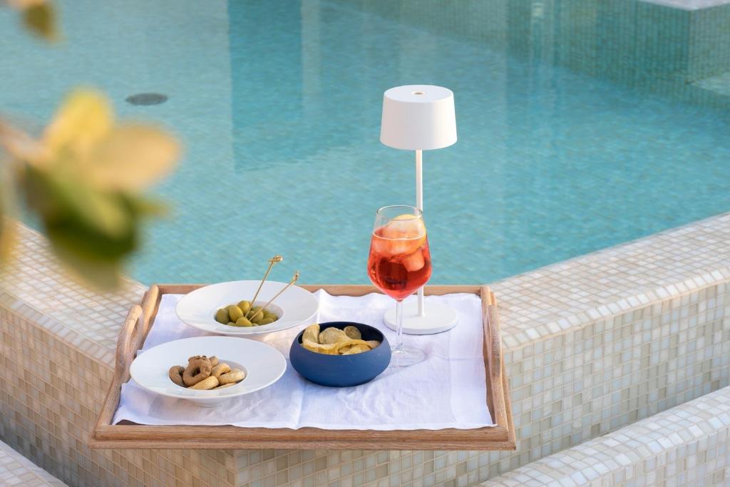 a table with a drink and plates of food next to a pool at Palazzo del Corso – Boutique Hotel in Gallipoli