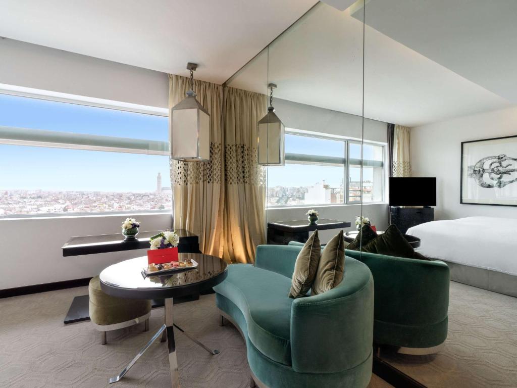a hotel room with a bed and a couch and a table at Sofitel Casablanca Tour Blanche in Casablanca