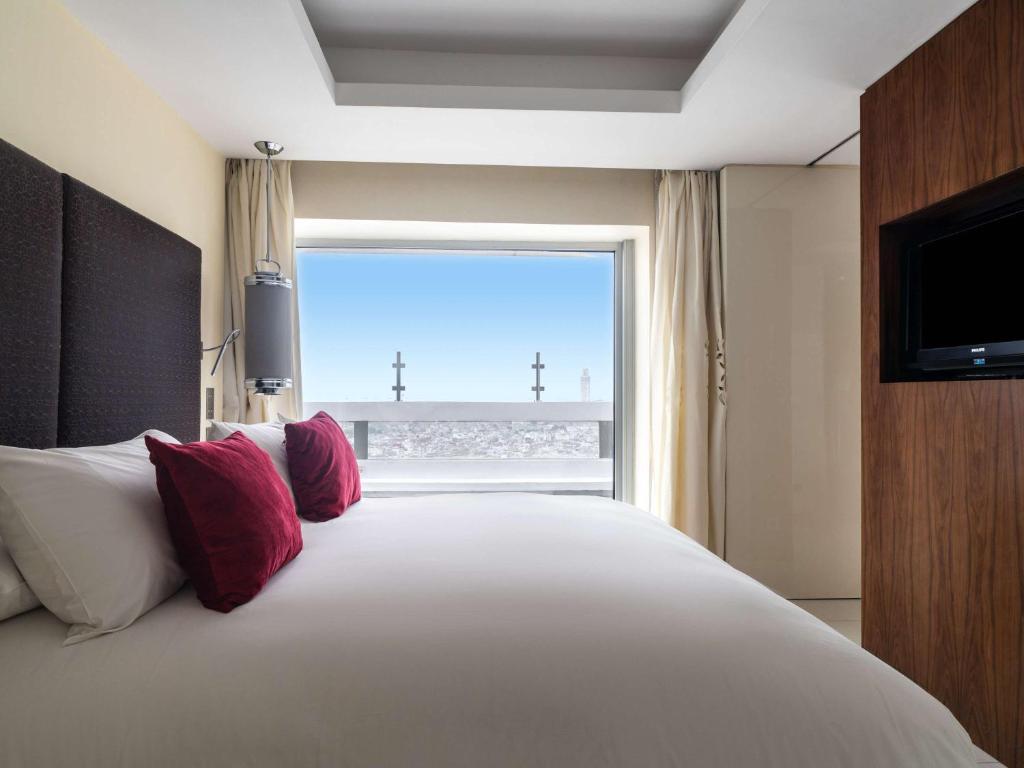 a bedroom with a large bed with a large window at Sofitel Casablanca Tour Blanche in Casablanca