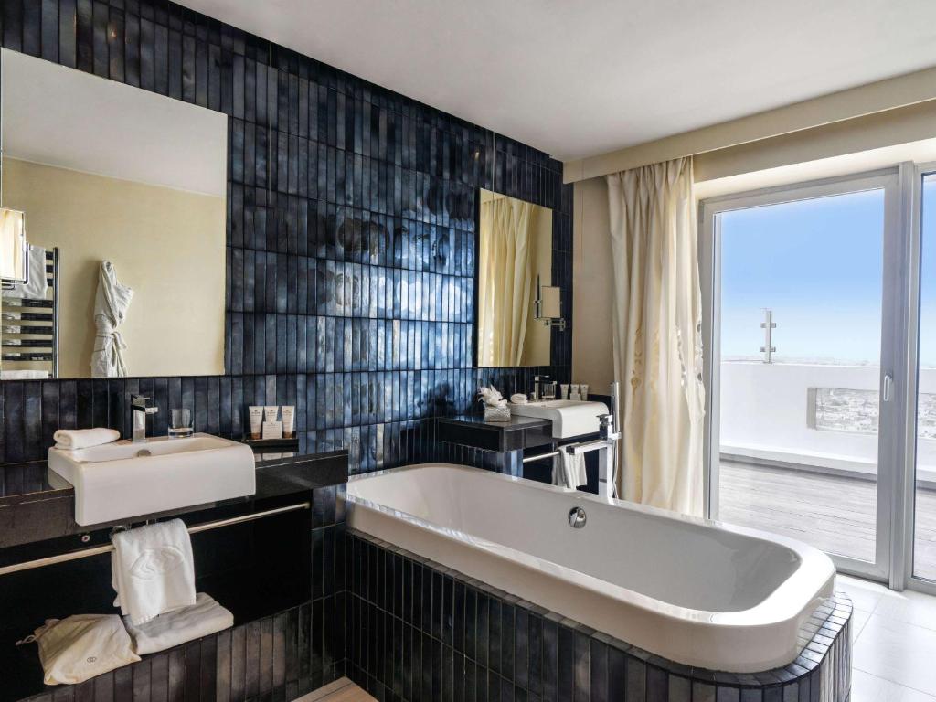 a bathroom with a tub and a sink and a mirror at Sofitel Casablanca Tour Blanche in Casablanca
