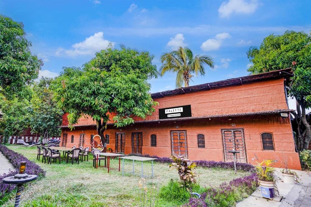 a building with tables and chairs in front of it at Palette by CheckIn Palghar Lifestyle Retreat Formerly Irayos Resort in Talāsri