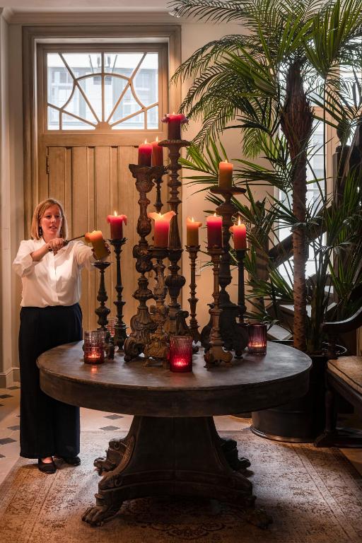 a woman standing next to a table with candles on it at The Notary in Bruges