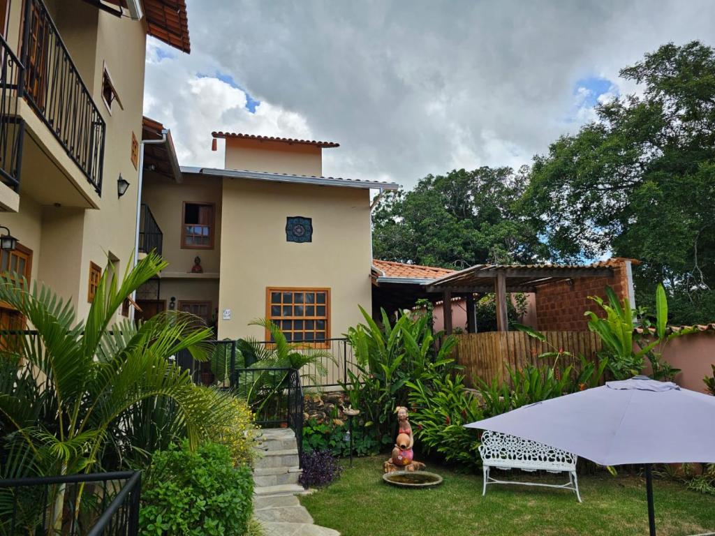 a yard with an umbrella and a house at Pousada Mãe Natureza in Pirenópolis