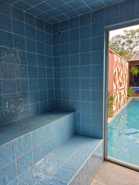 a room with a blue tiled wall next to a swimming pool at Pousada Mãe Natureza in Pirenópolis