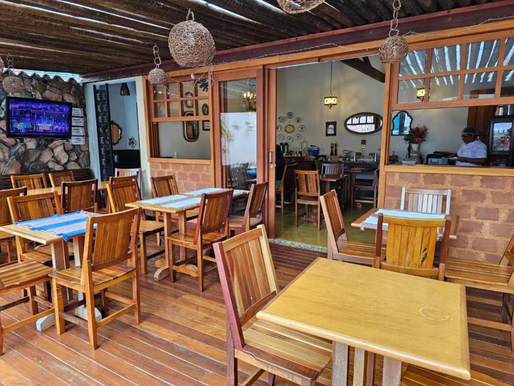 a restaurant with wooden tables and wooden chairs at Pousada Mãe Natureza in Pirenópolis