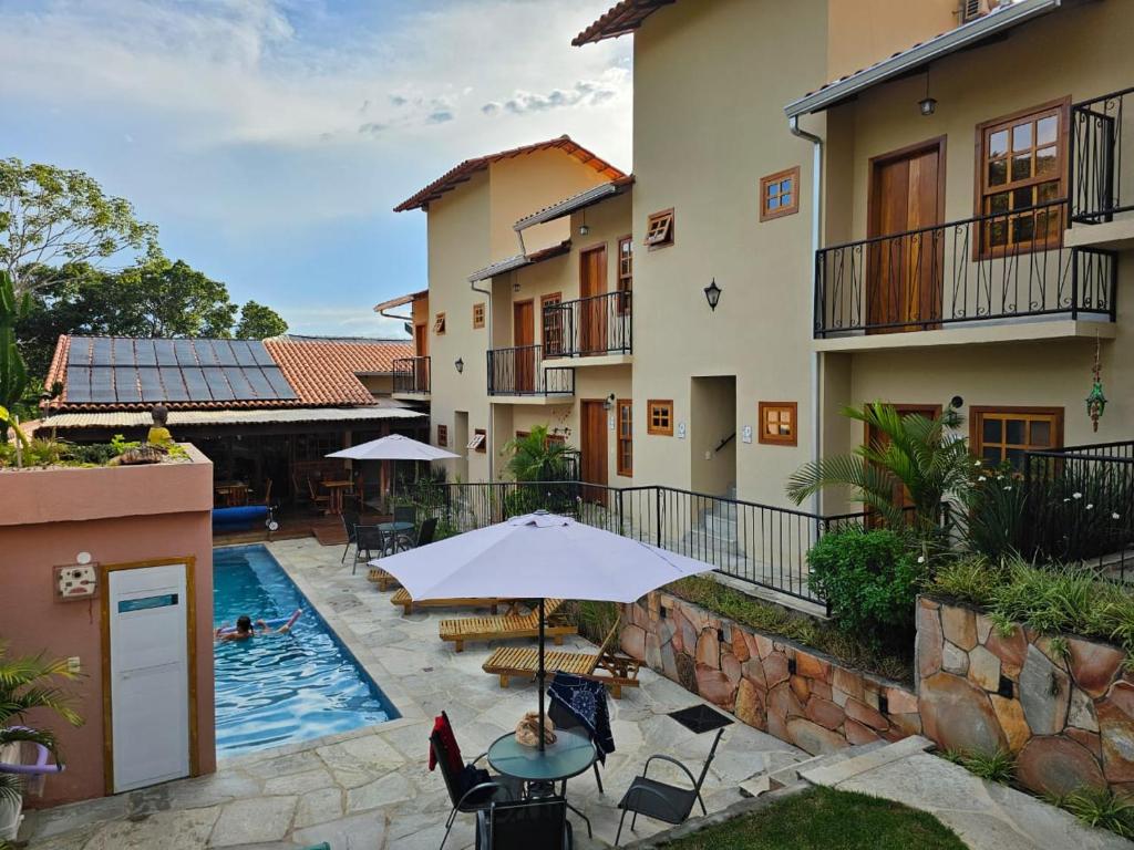 an outdoor patio with an umbrella and a swimming pool at Pousada Mãe Natureza in Pirenópolis