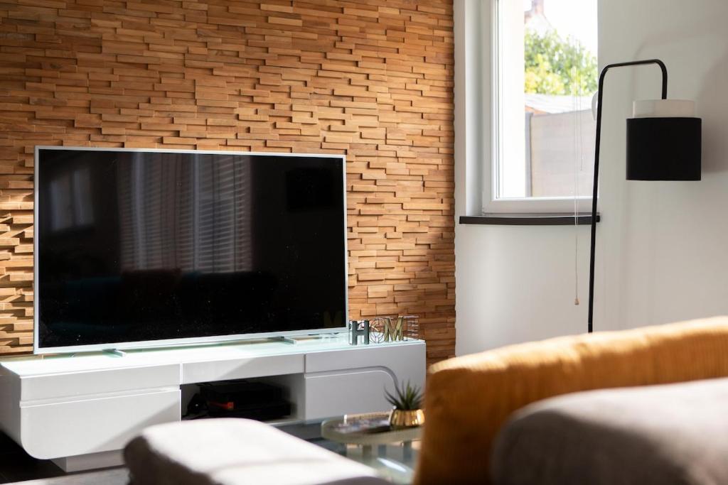 un salon avec une grande télévision sur un mur en briques dans l'établissement Eclipse SPA jeux Cinema Colmar, à Muntzenheim