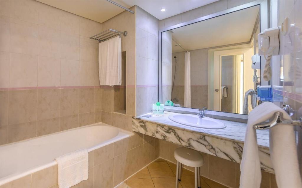 a bathroom with a tub and a sink and a mirror at Marhaba Royal Salem - Family Only in Sousse