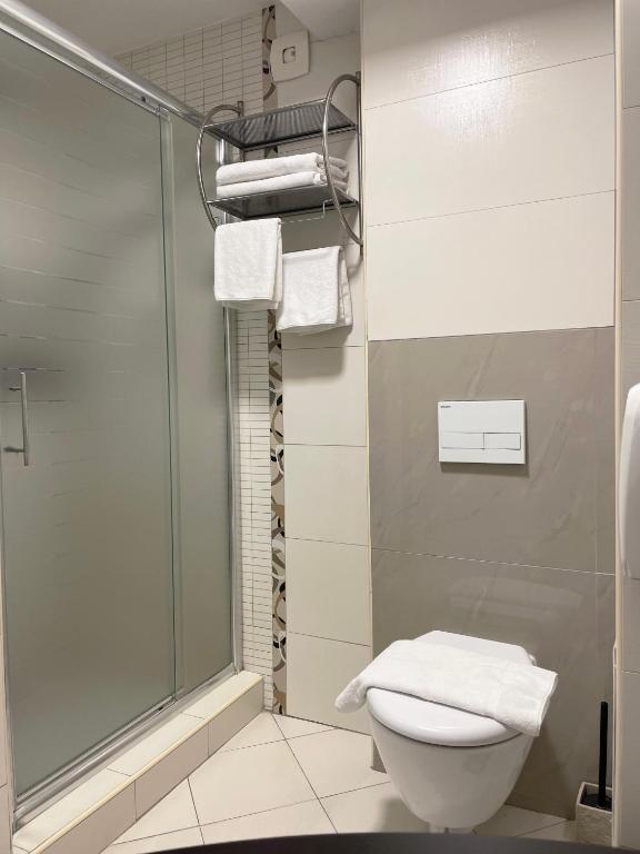 a bathroom with a shower and a toilet and towels at Sienna Apartments in Skopje