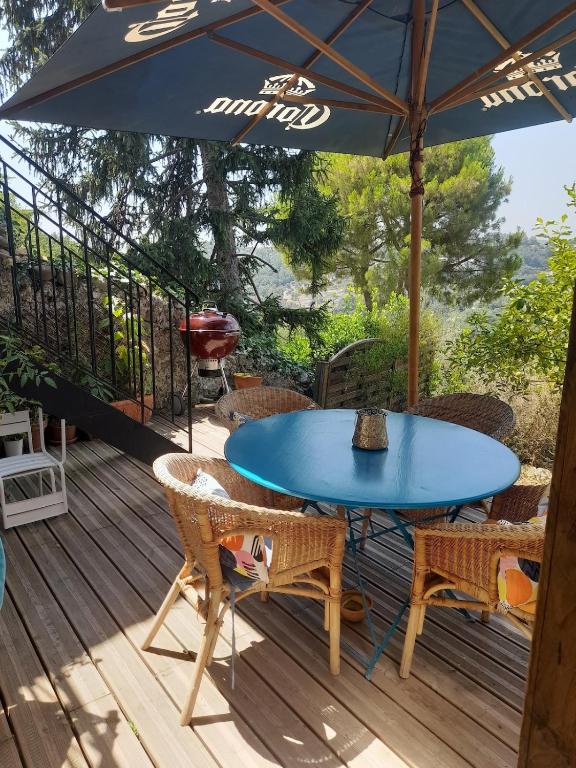une table et des chaises bleues sur une terrasse avec un parasol dans l'établissement Village house surrounded by greenery, à La Gaude