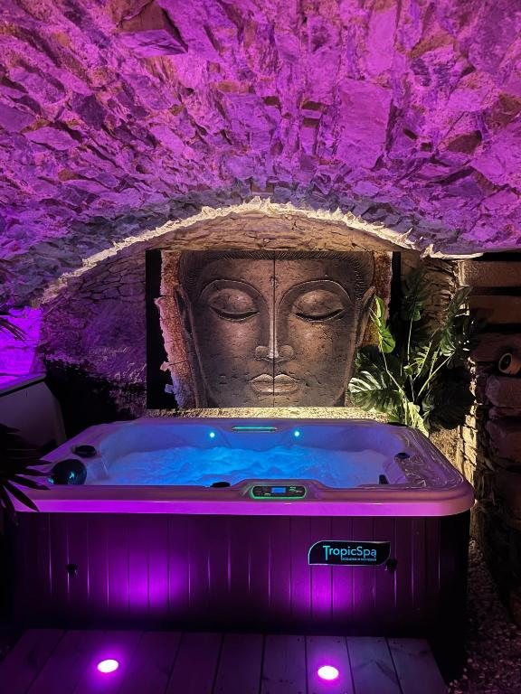 wanna z posągiem w pokoju z fioletowym oświetleniem w obiekcie La Voûte du Pilat & options SPA, massage w mieście Saint-Chamond