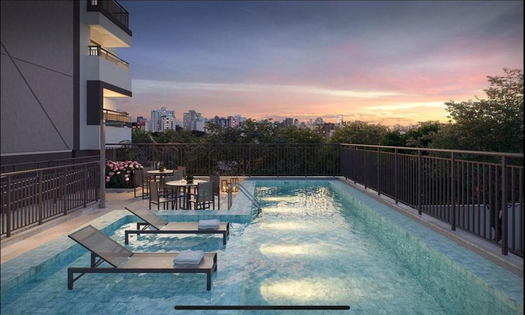 a swimming pool with chairs and a table on a building at Studio 1106 Raizes Tucuruvi- Proximo ao shopping in Sao Paulo
