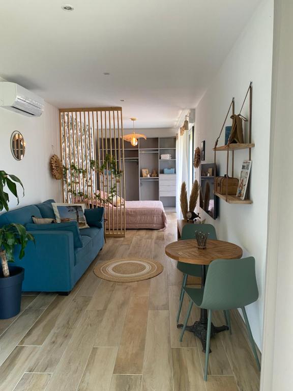 un salon avec un canapé bleu et une table dans l'établissement Studio cosy & piscine privée, à Villanova