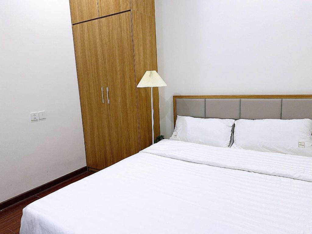 a bedroom with a white bed with a wooden cabinet at Căn Hộ 2 Phòng Ngủ LUXURY-1816 in Gia Lâm Pho