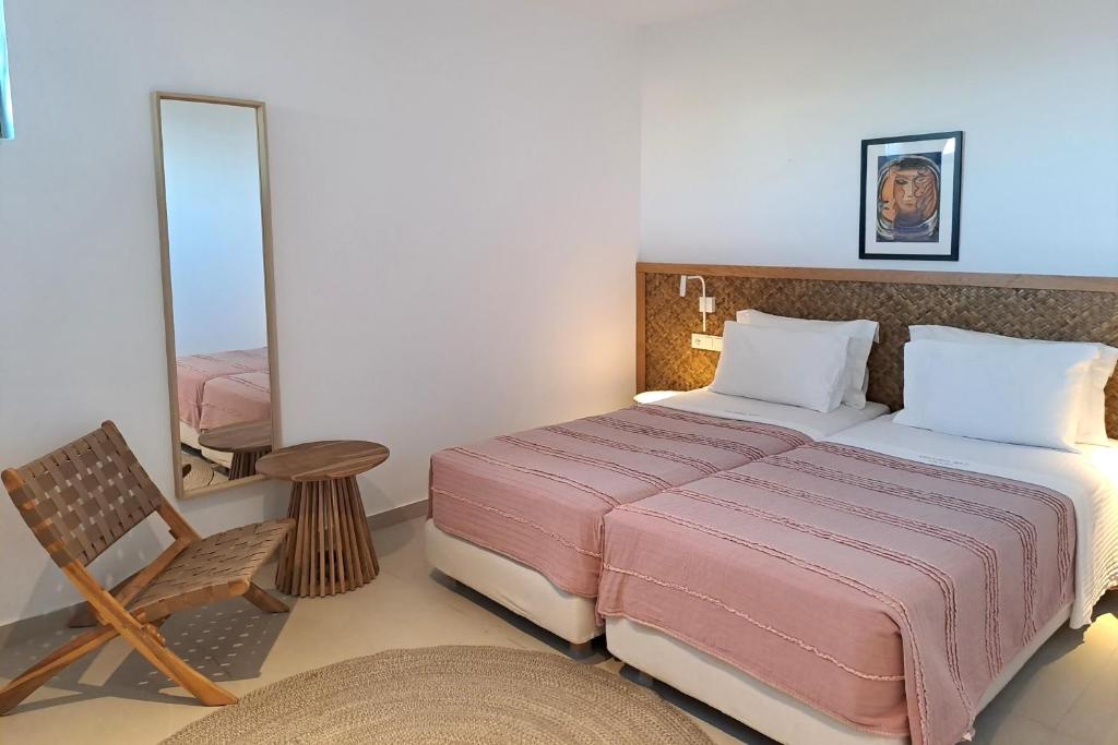 a bedroom with a bed and a chair and a mirror at Kechria Bay Villas in Skiathos