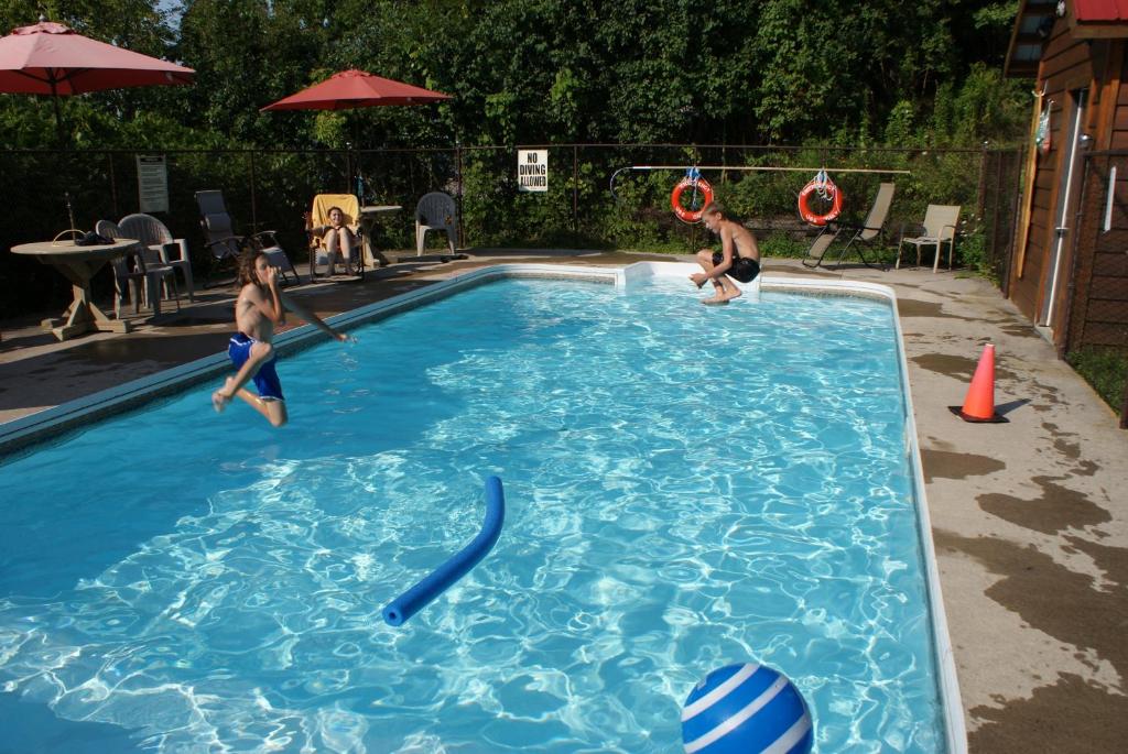 deux garçons jouant dans une piscine dans une arrière-cour dans l'établissement Sandy Shore Cottages, à Harwood