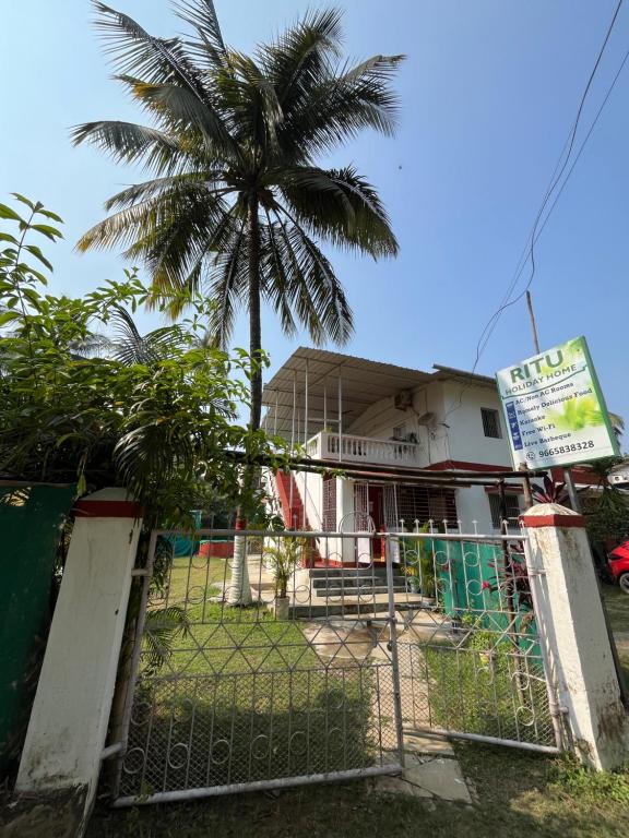 a gate in front of a house with a palm tree at Ritu Holiday Home - Nagaon in Nagaon