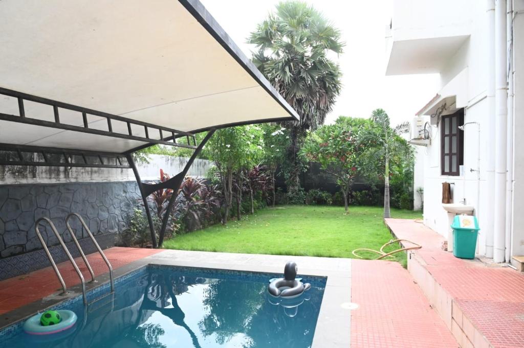 una piscina con sombrilla junto a un patio en Pearl House Villa Panayur ECR Beach, Chennai, en Chennai