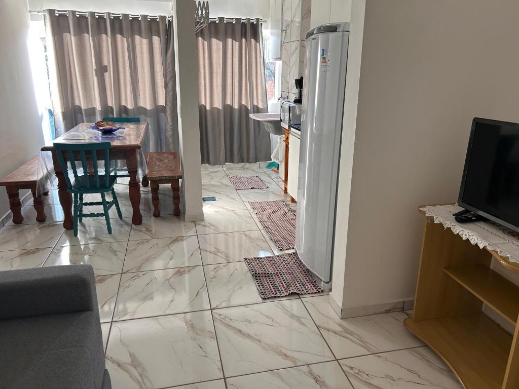 a living room with a table and a refrigerator at Apto Bela Vista 10 in Pôrto Ferreira