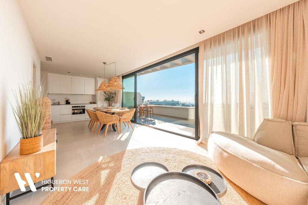 a living room with a couch and a table with a kitchen at Higueron West Property Collection - La CostaVale by HWPC in Fuengirola