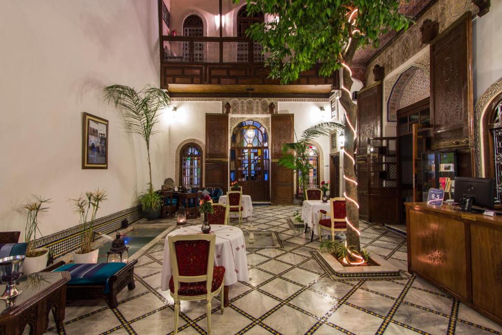 Riad Les Remparts De Fès في فاس: مطعم بطاولات وكراسي في مبنى