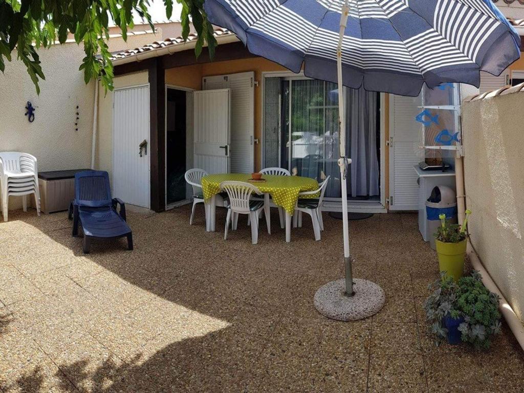 un patio avec une table, des chaises et un parasol dans l'établissement Villa Cap d'Agde : Plage à pied, piscine, parking, terrasse - FR-1-723-140, au Cap d'Agde