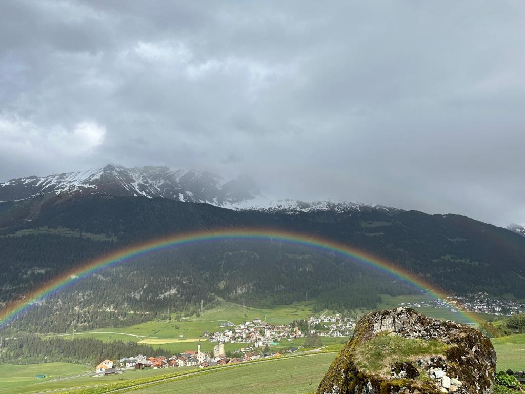 a rainbow over a town in a valley with mountains at Ferienwohnung Visoura in Reams