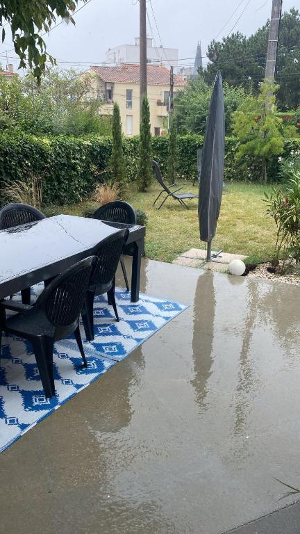 une table, des chaises et un parasol sous la pluie dans l'établissement les peupliers, à Royan