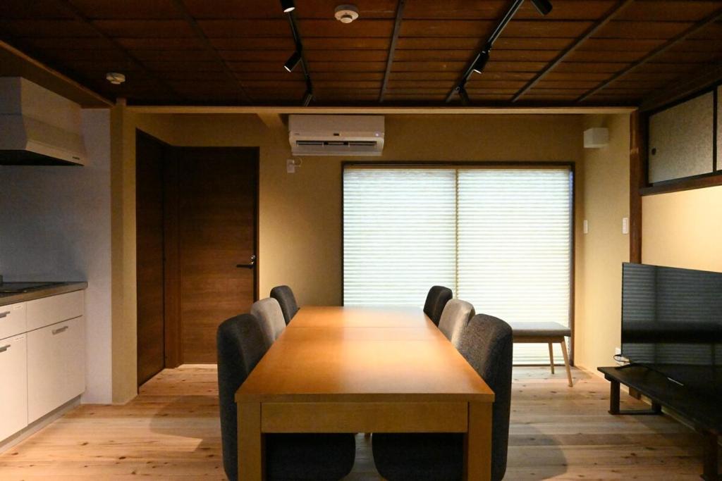 a conference room with a wooden table and chairs at Manabi-stay Matsue 駅近伊勢宮町どこに行くにも最高に便利な古民家一棟貸切ホテル in Matsue