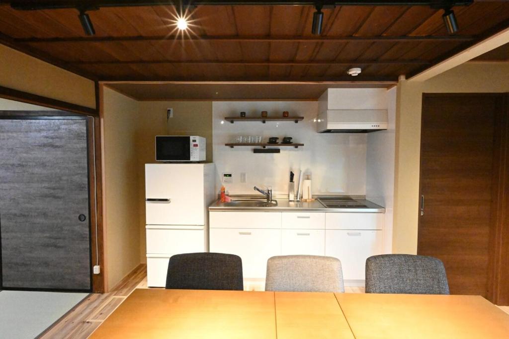 a kitchen with white cabinets and a table and chairs at Manabi-stay Matsue 駅近伊勢宮町どこに行くにも最高に便利な古民家一棟貸切ホテル in Matsue