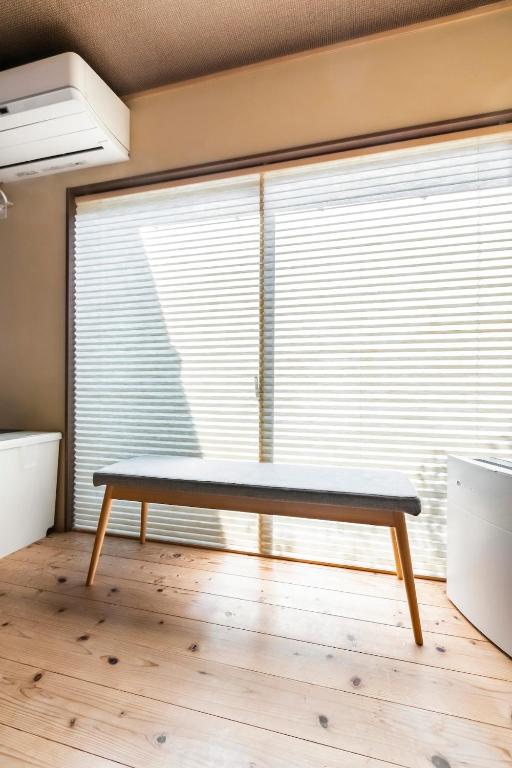 a bench in a room with a window with blinds at Manabi-stay Matsue 駅近伊勢宮町どこに行くにも最高に便利な古民家一棟貸切ホテル in Matsue