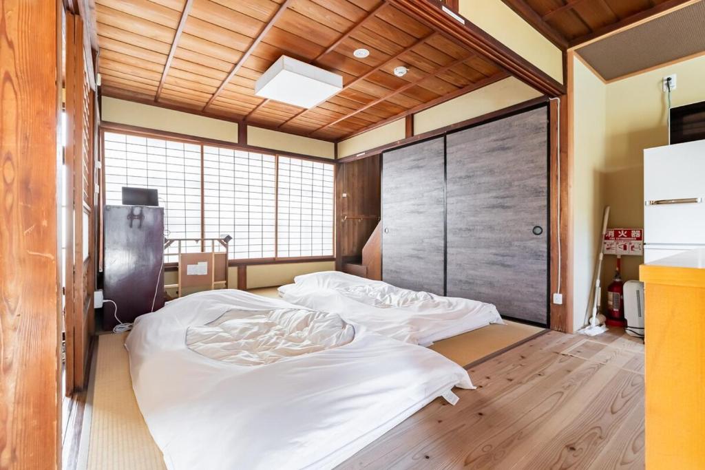 a bedroom with a large white bed in it at Manabi-stay Matsue 駅近伊勢宮町どこに行くにも最高に便利な古民家一棟貸切ホテル in Matsue