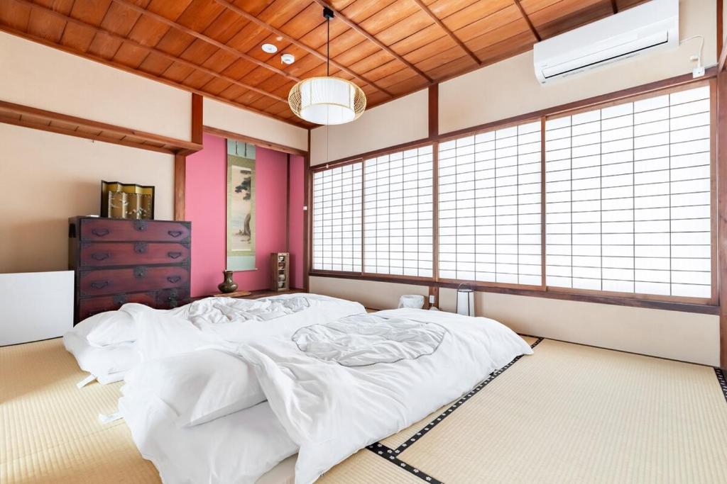 a bedroom with a large bed in a room with windows at Manabi-stay Matsue 駅近伊勢宮町どこに行くにも最高に便利な古民家一棟貸切ホテル in Matsue