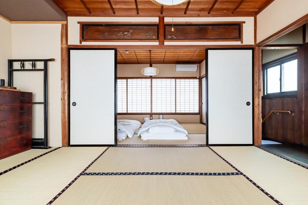 a bedroom with two beds in a room with doors at Manabi-stay Matsue 駅近伊勢宮町どこに行くにも最高に便利な古民家一棟貸切ホテル in Matsue