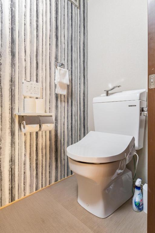 a white toilet in a bathroom with a curtain at Manabi-stay Matsue 駅近伊勢宮町どこに行くにも最高に便利な古民家一棟貸切ホテル in Matsue
