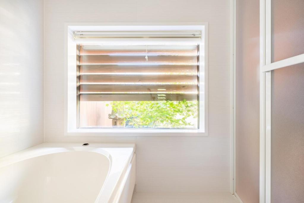 a bathroom with a window and a tub and a sink at Manabi-stay Matsue 駅近伊勢宮町どこに行くにも最高に便利な古民家一棟貸切ホテル in Matsue