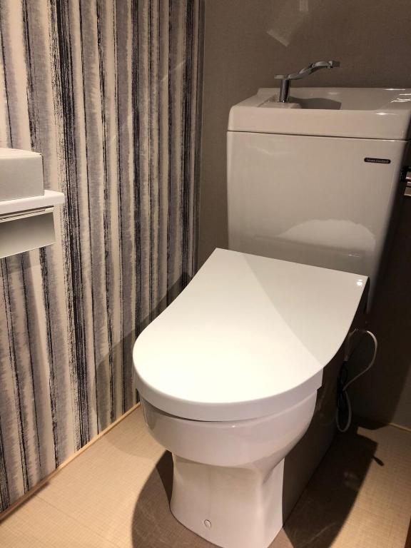 a white toilet in a bathroom with a shower curtain at Manabi-stay Matsue 駅近伊勢宮町どこに行くにも最高に便利な古民家一棟貸切ホテル in Matsue