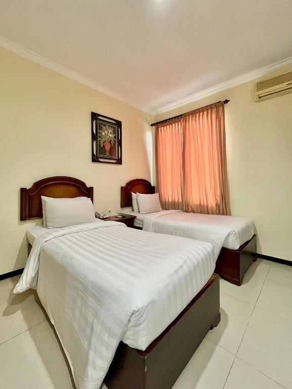 Postel nebo postele na pokoji v ubytování Tuwuh Hotel at Kayutangan