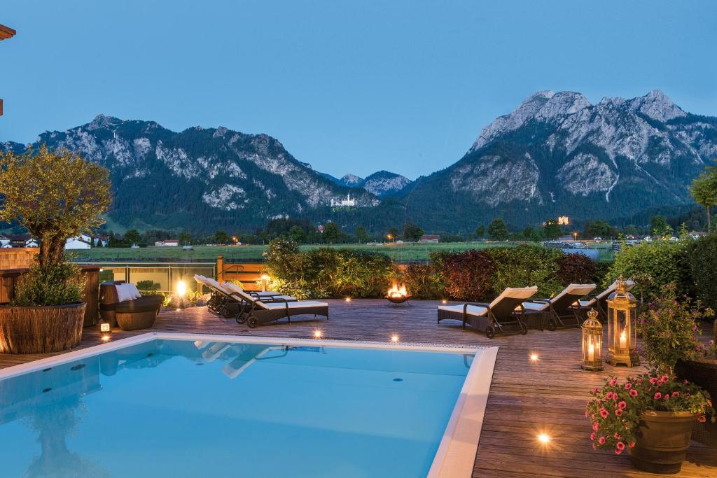uma piscina com montanhas ao fundo em Hotel Das Rübezahl em Schwangau