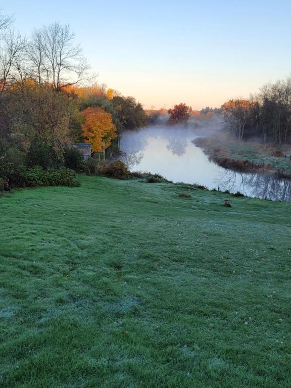 a grassy field with a pond in the background at A River Runs Through It in Napanee