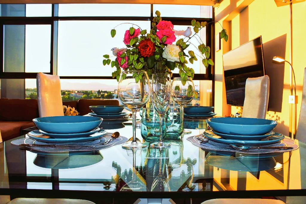a glass table with blue plates and a vase of flowers at Dúplex Icónico y Exclusivo en Madrid 6pax AirPort in San Sebastián de los Reyes