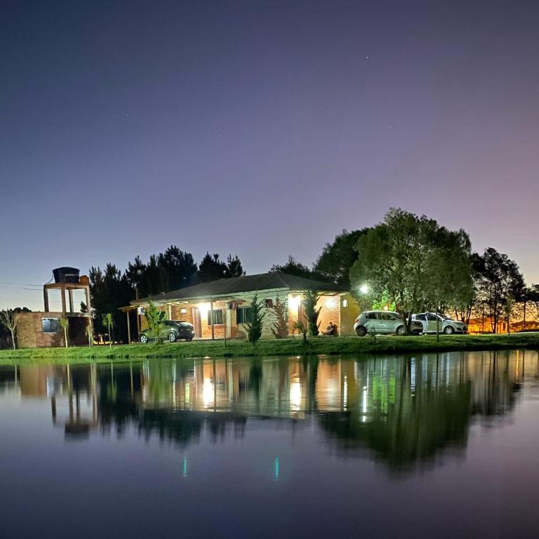 a house with two cars parked in front of a lake at Cânions de Cambará in Cambará