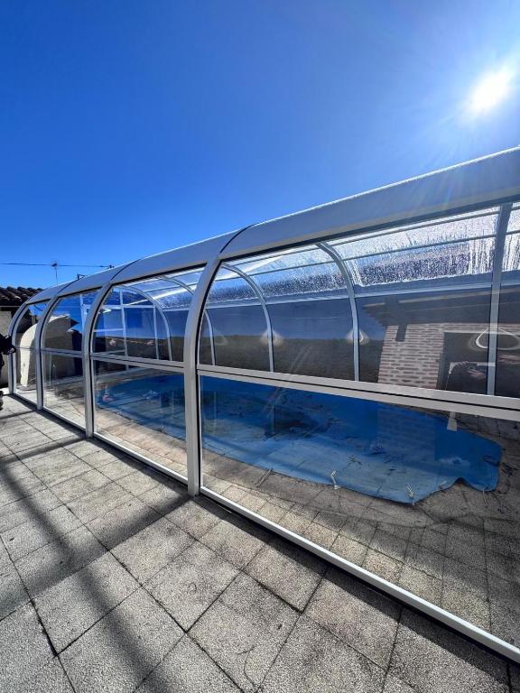 a glass building with a pool of blue water at blasón conde de castro in Santo Tomé de Zabarcos
