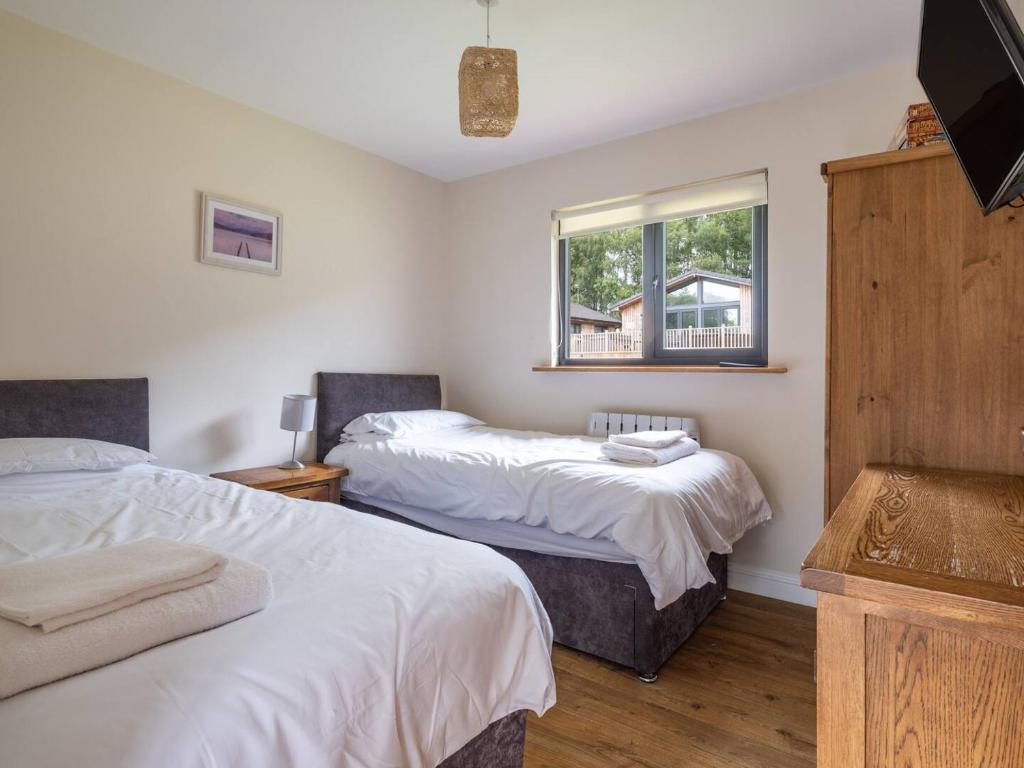a bedroom with two beds and a window at Cabin W Hot Tub, Outdoor Dining In National Park in Otterburn