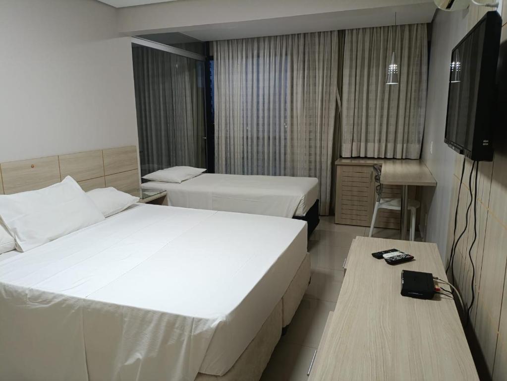 a hotel room with two beds and a television at Garvey - flat 638 in Brasilia