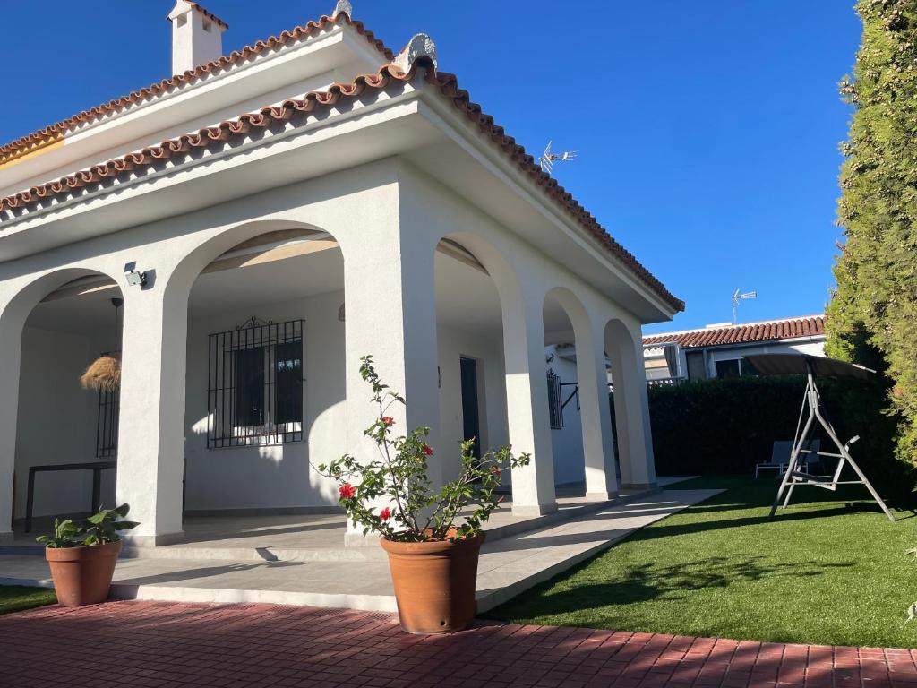 een wit huis met twee potplanten in een tuin bij Tu casa en Doñana in Matalascañas