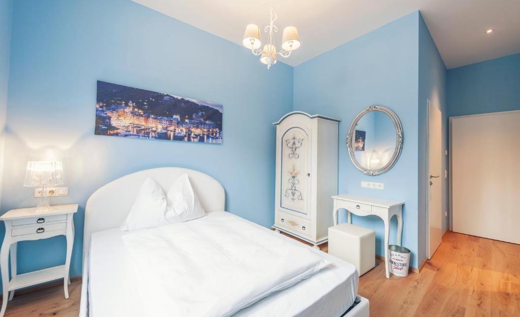 a blue bedroom with a white bed and a mirror at La Cucina - Hotel & Restaurant in Peggau