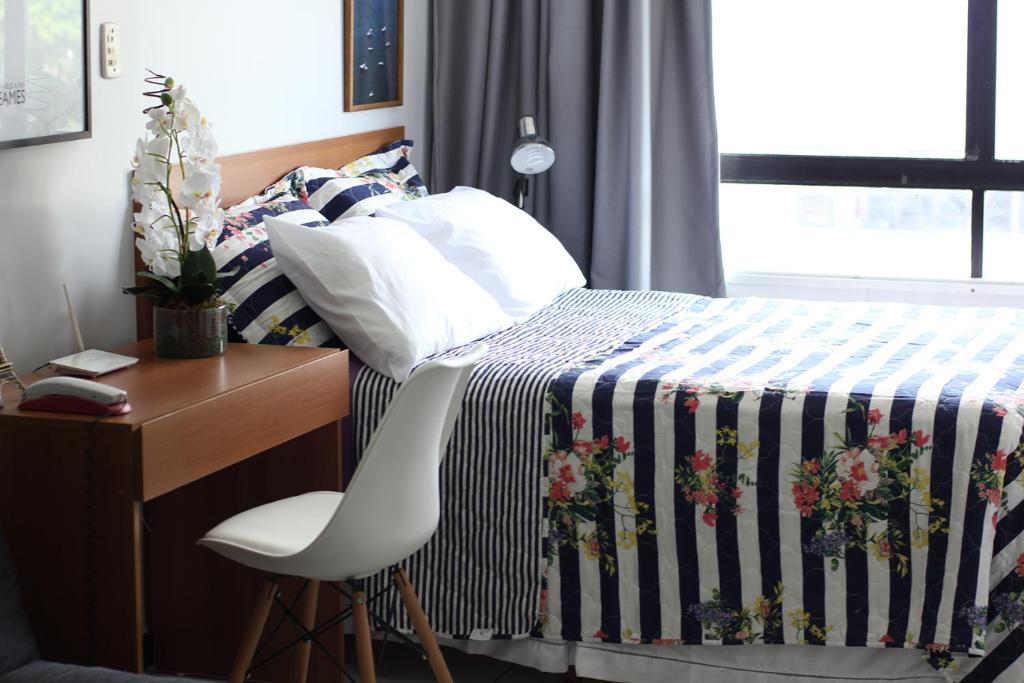 1 dormitorio con 1 cama con escritorio y silla blanca en Flat Farol da Barra, en Salvador